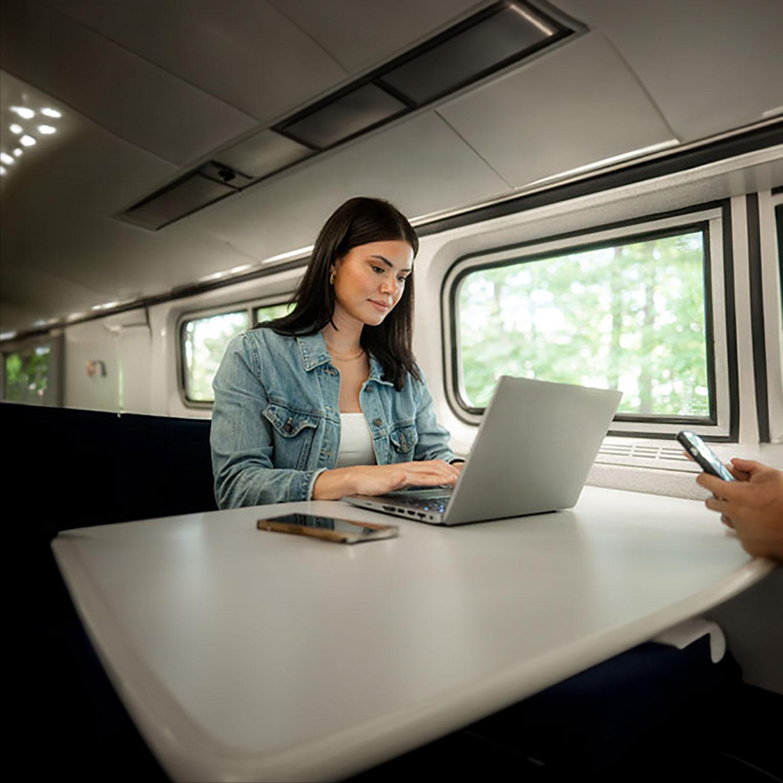 Person working on a laptop on an Amtrak Cascades train