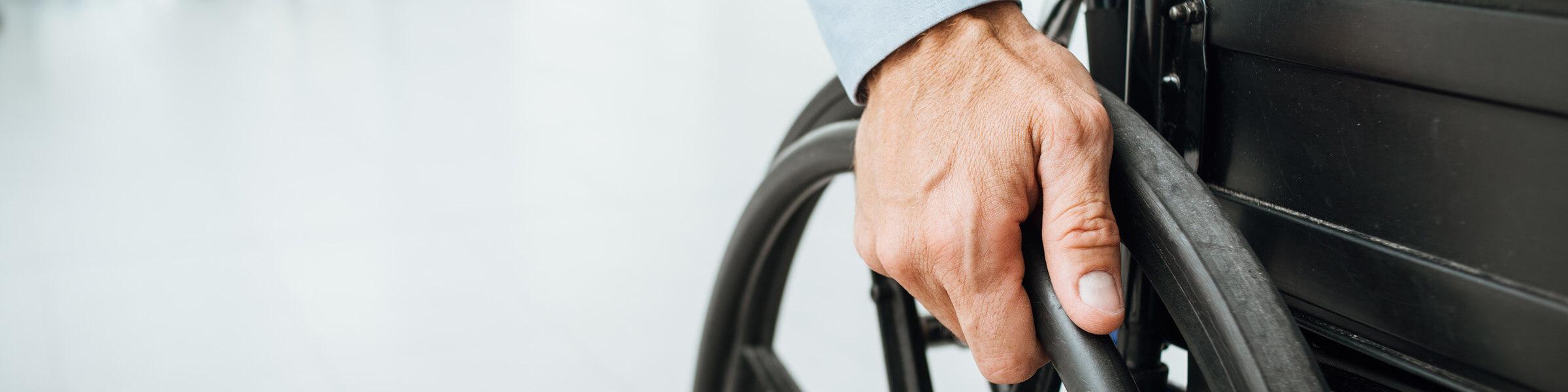 Person's hand on a mobility wheel