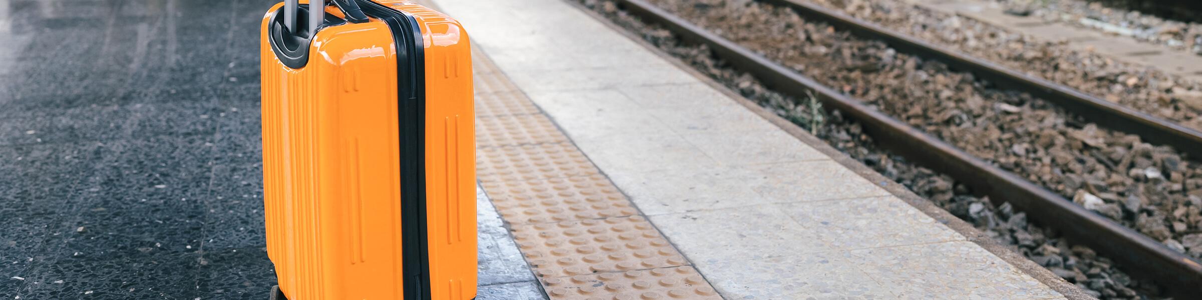 An orange suitcase on the train platform