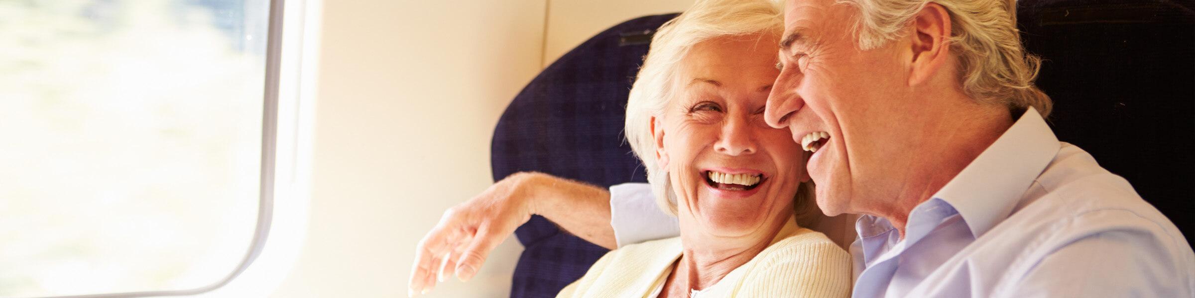 A man and a woman sitting on the train, smiling