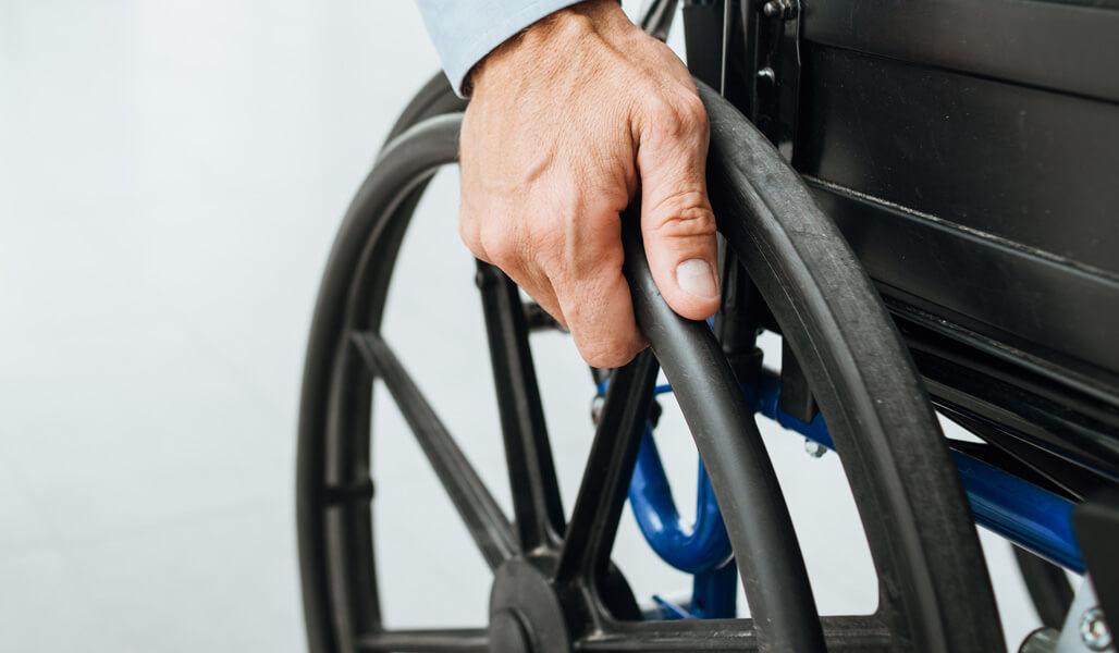 Person's hand on a mobility wheel