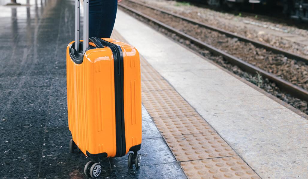 An orange suitcase on the train platform