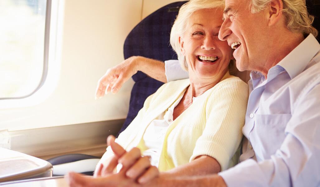A man and a woman sitting on the train, smiling