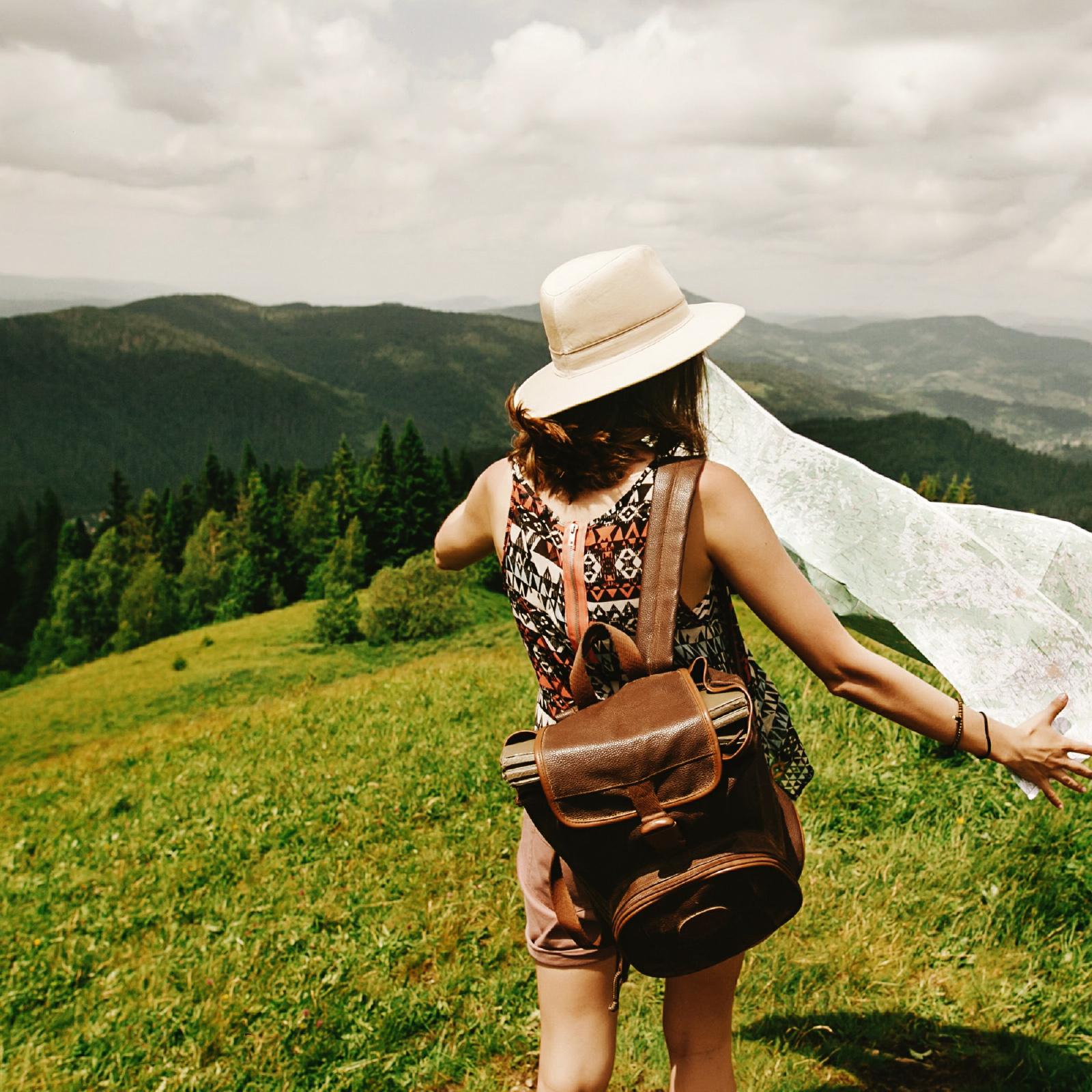 Person with a flowing open map on a hillside vista